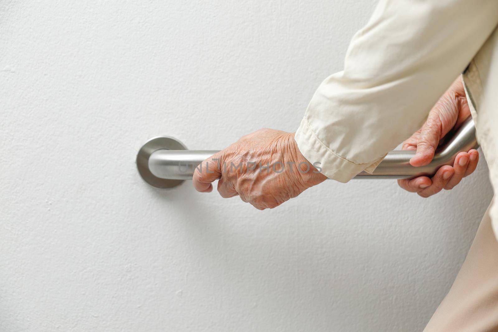 Elderly woman holding on handrail for safety walk steps