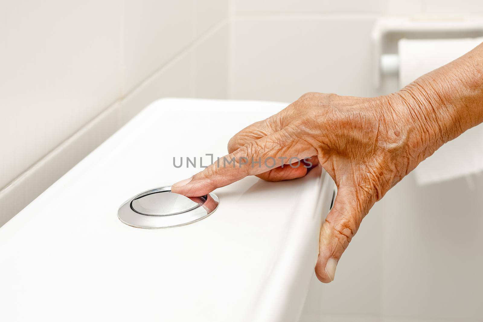 Elderly woman hand flushing toilet