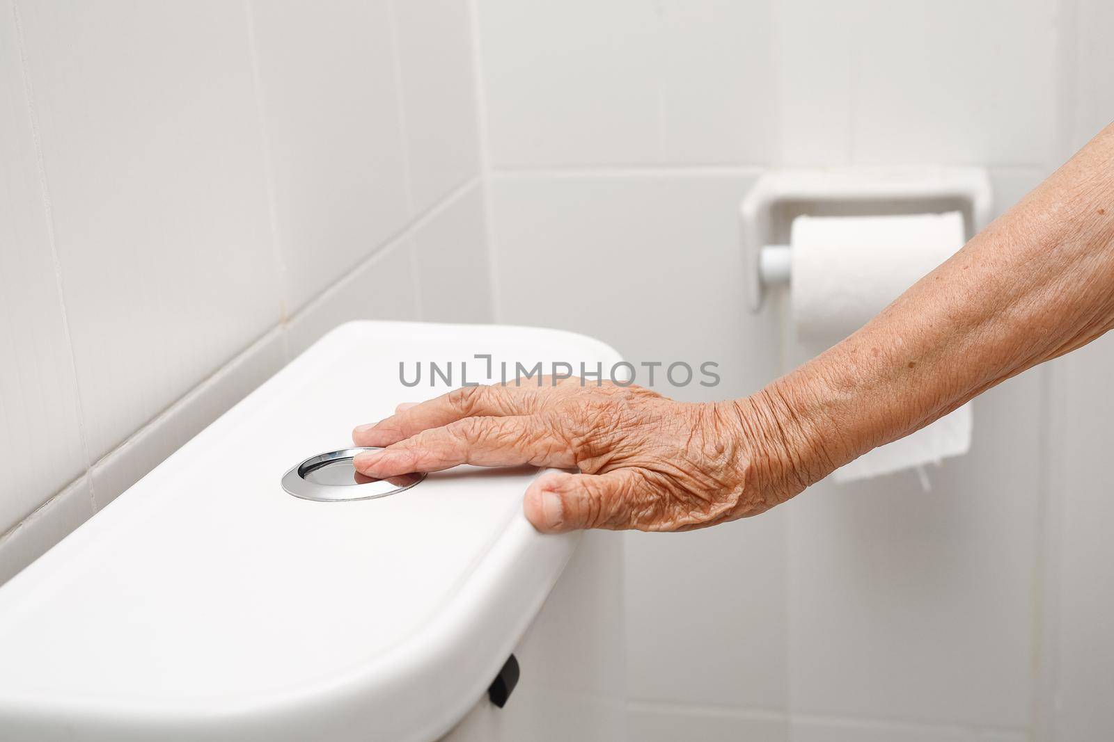 Elderly woman hand flushing toilet