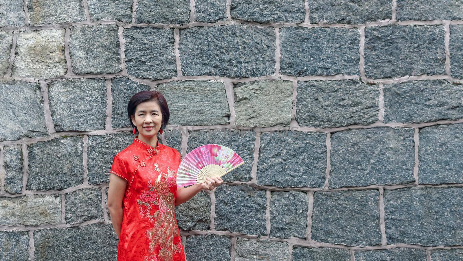 Solo female tourist in chinese traditional clothing with stone wall