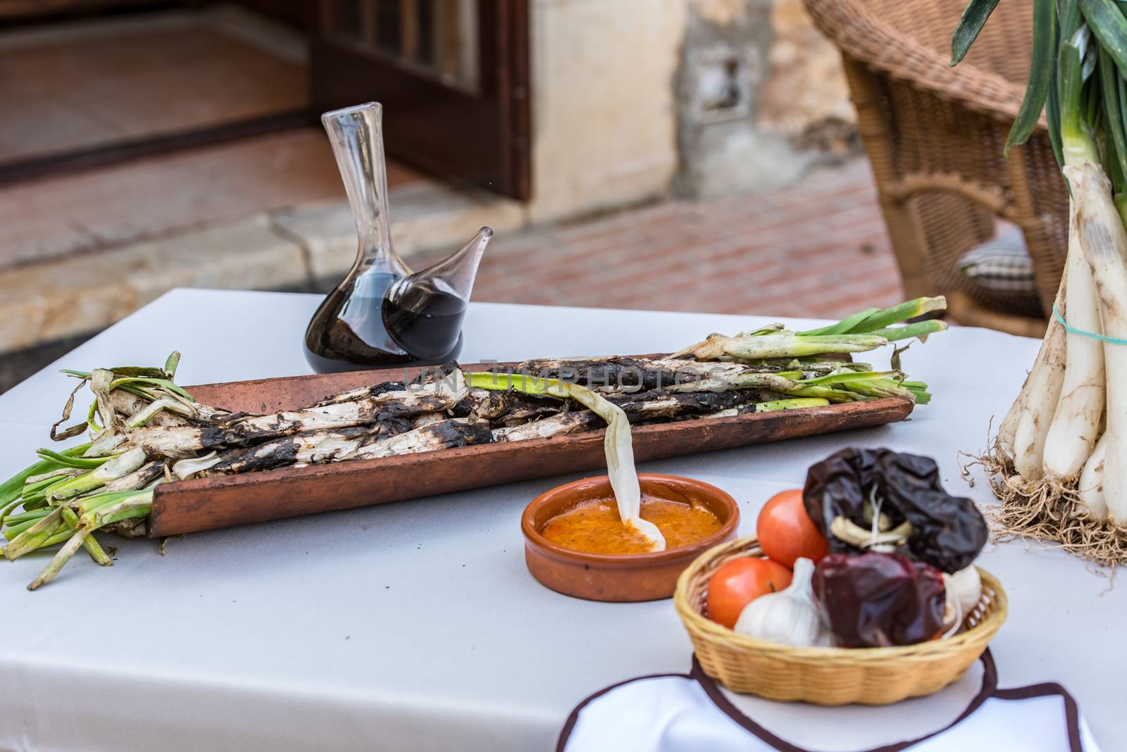 Roasted Calcots onions served on plate with Romesco sauce – traditional Catalan winter dish.