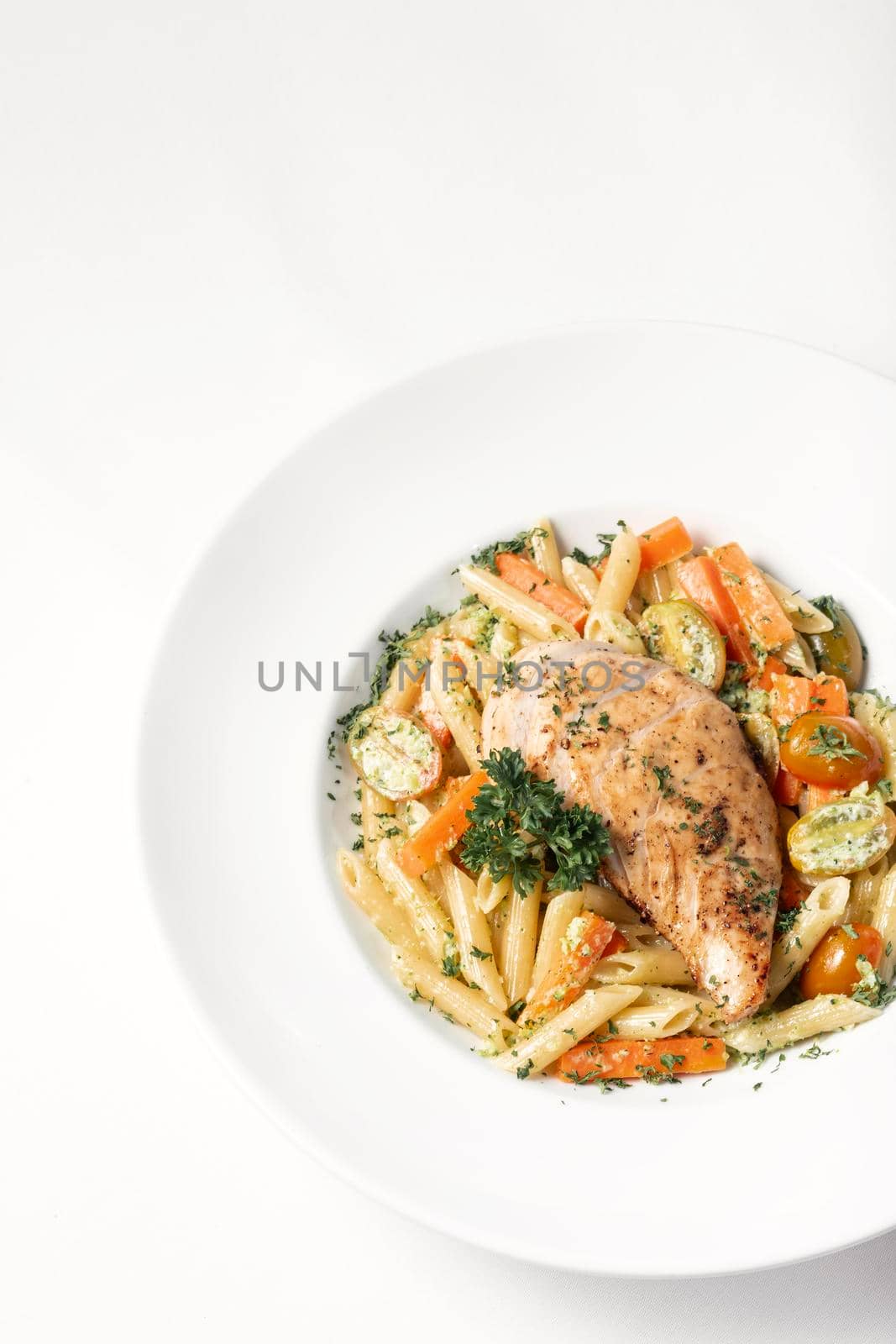 fried chicken breast with penne and saute vegetables pasta dish on white background