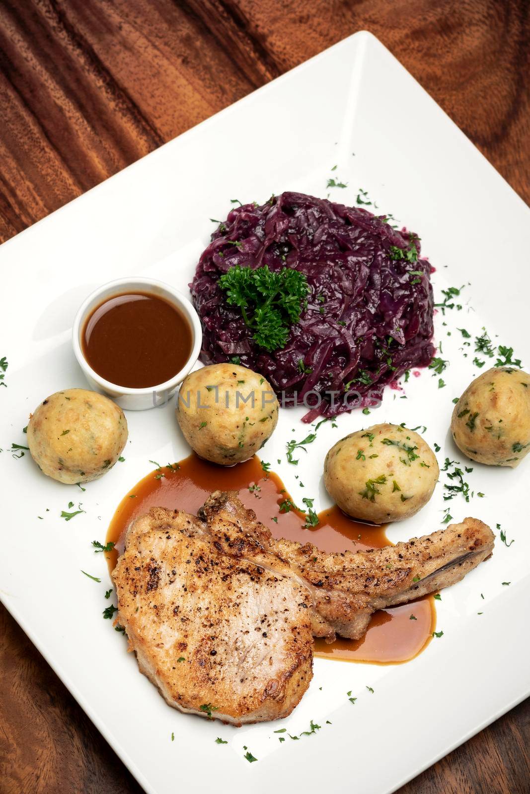 german style grilled pork chop with bread dumplings and red cabbage traditional meal on wood table