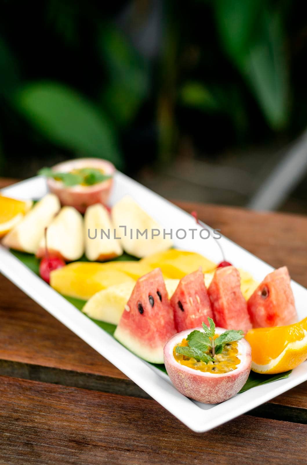 mixed fresh cut organic fruit salad platter outdoors on wood table