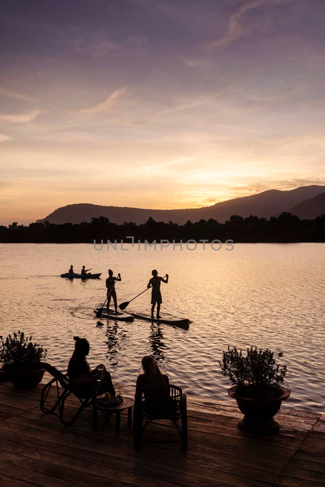 kampot river view in cambodia with SUP stand up paddle boarding tourists at sunset