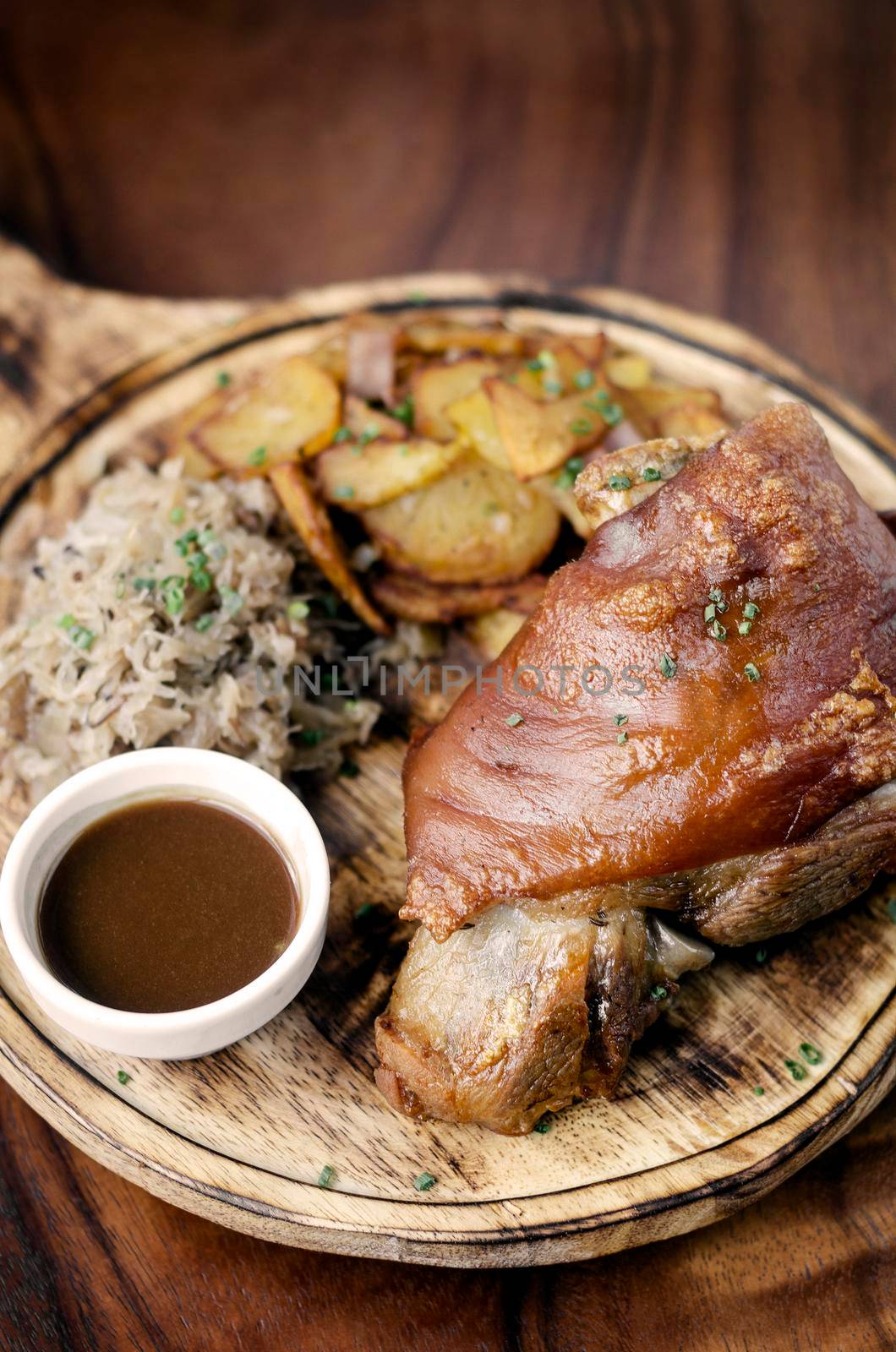 SCHWEINSHAXE traditional german pork knuckle with sauerkraut and potatoes bavarian meal on rustic wood background