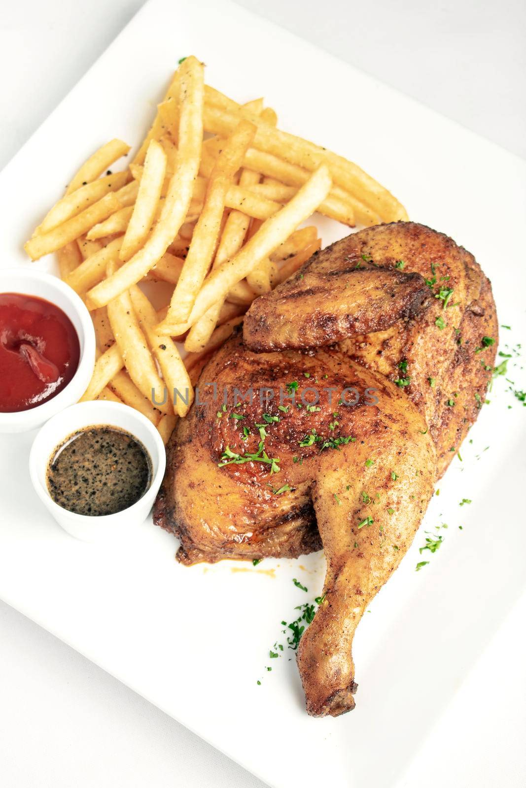 roast rotisserie half chicken with french fries simple meal on white plate