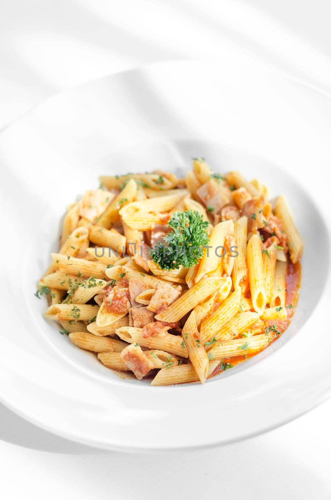 penne amatriciana tomato and ham sauce pasta on white table by jackmalipan