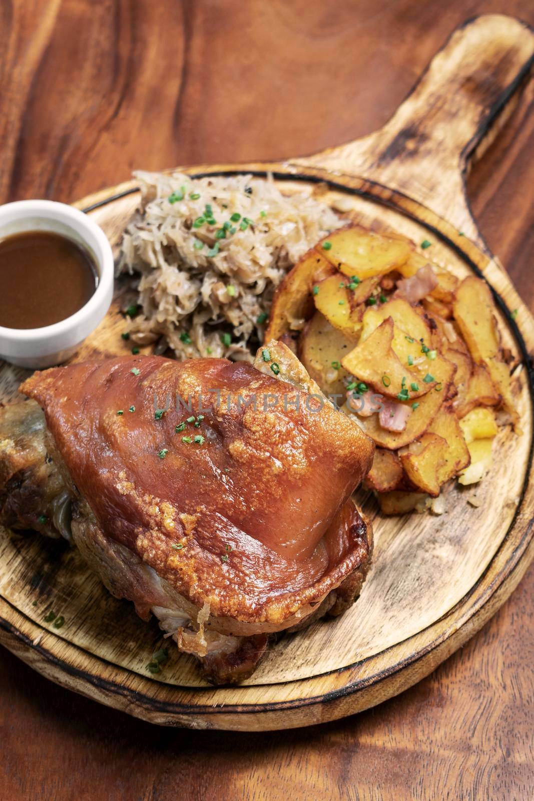 SCHWEINSHAXE traditional german pork knuckle with sauerkraut and potatoes bavarian meal on rustic wood background