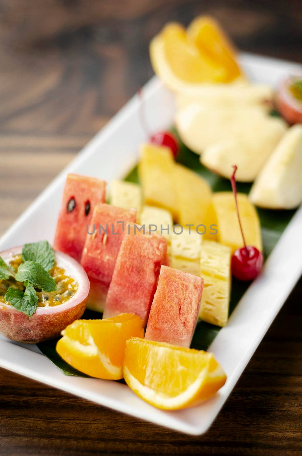 mixed fresh cut organic fruit salad platter outdoors on wood table