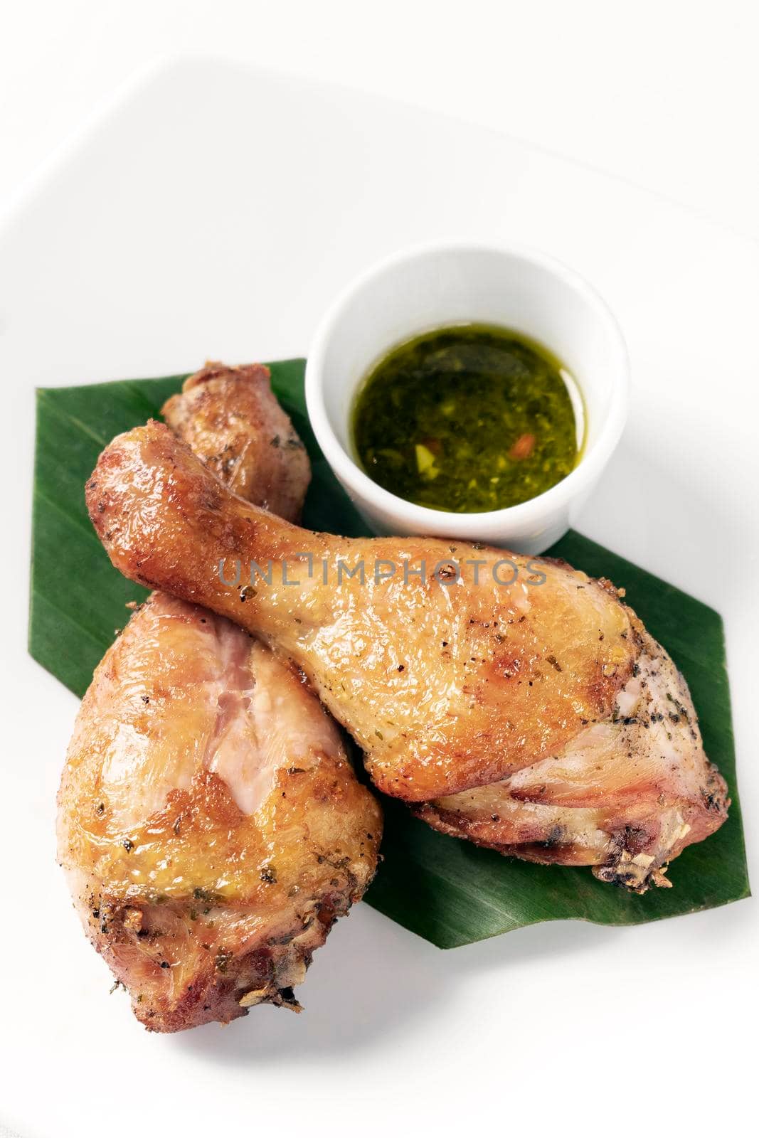 roast chicken drumsticks appetizer with spicy thai green chilli sauce on white background