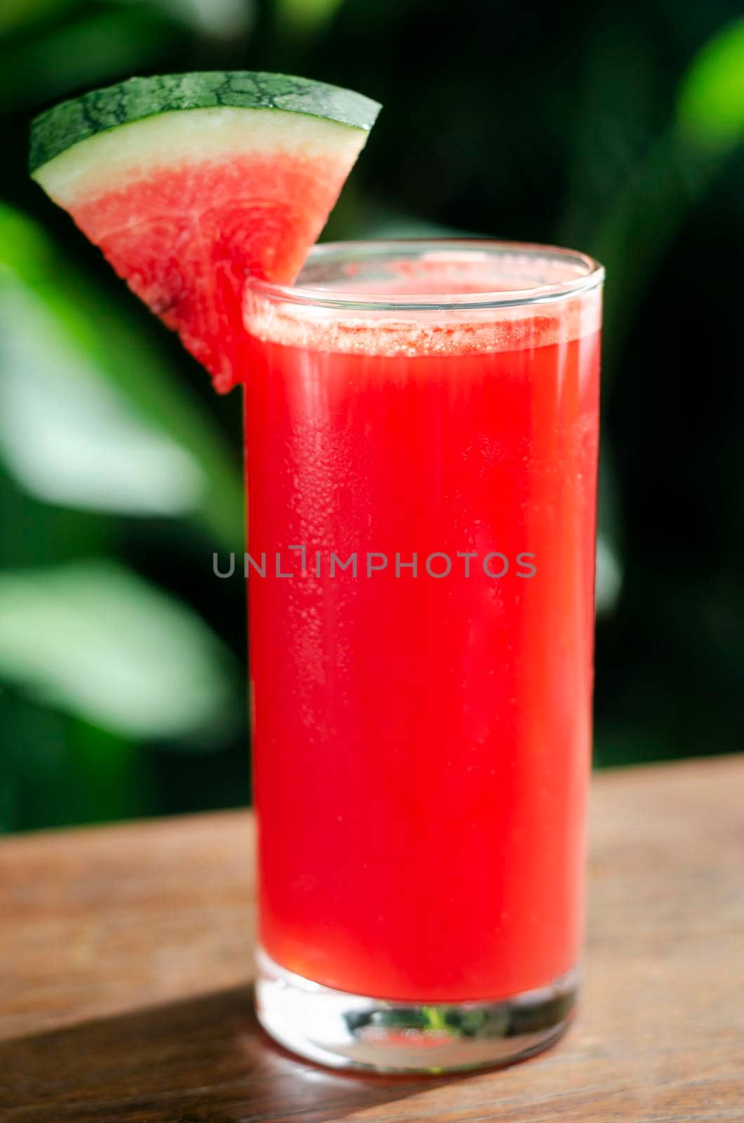 glass of fresh organic watermelon juice on garden table outdoors on sunny day