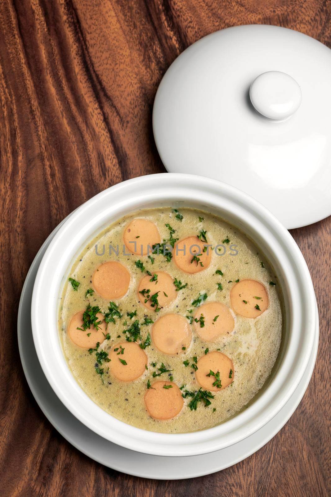 German traditional KARTOFFELSUPPE potato and sausage soup on wood table background