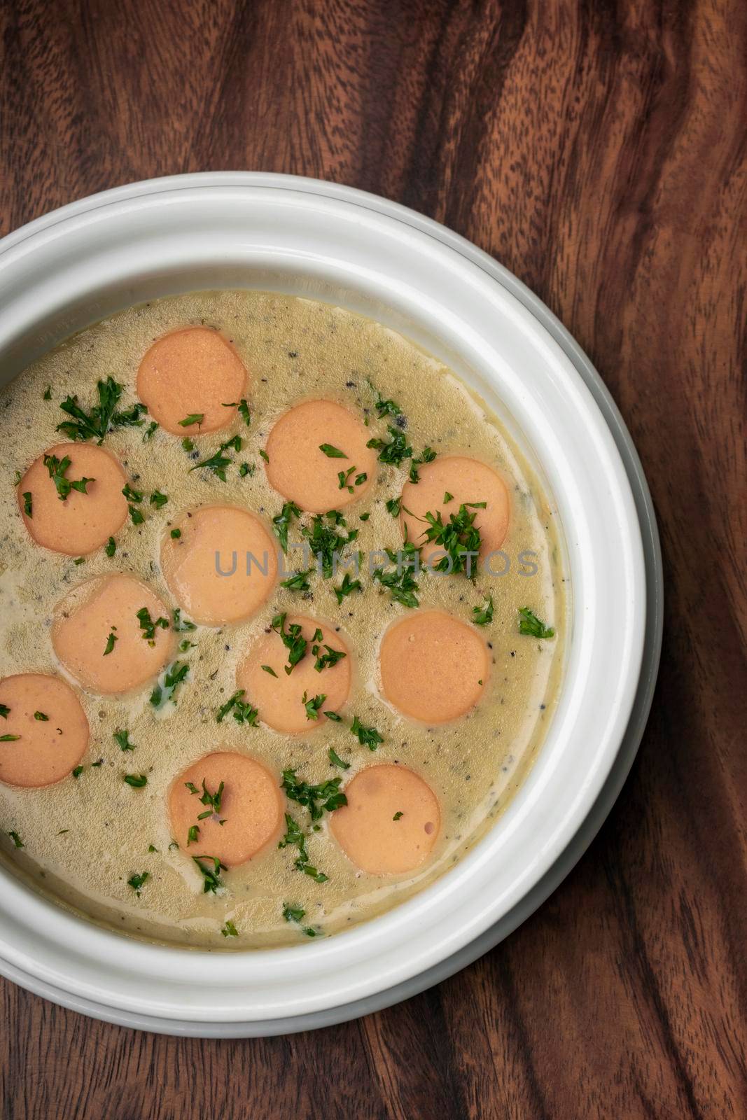 German traditional KARTOFFELSUPPE potato and sausage soup on wood table by jackmalipan