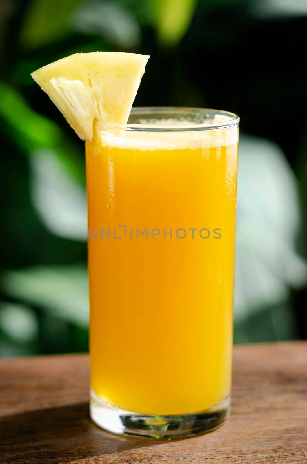 glass of fresh organic pineapple juice on table outdoors on table in sunny garden outdoors