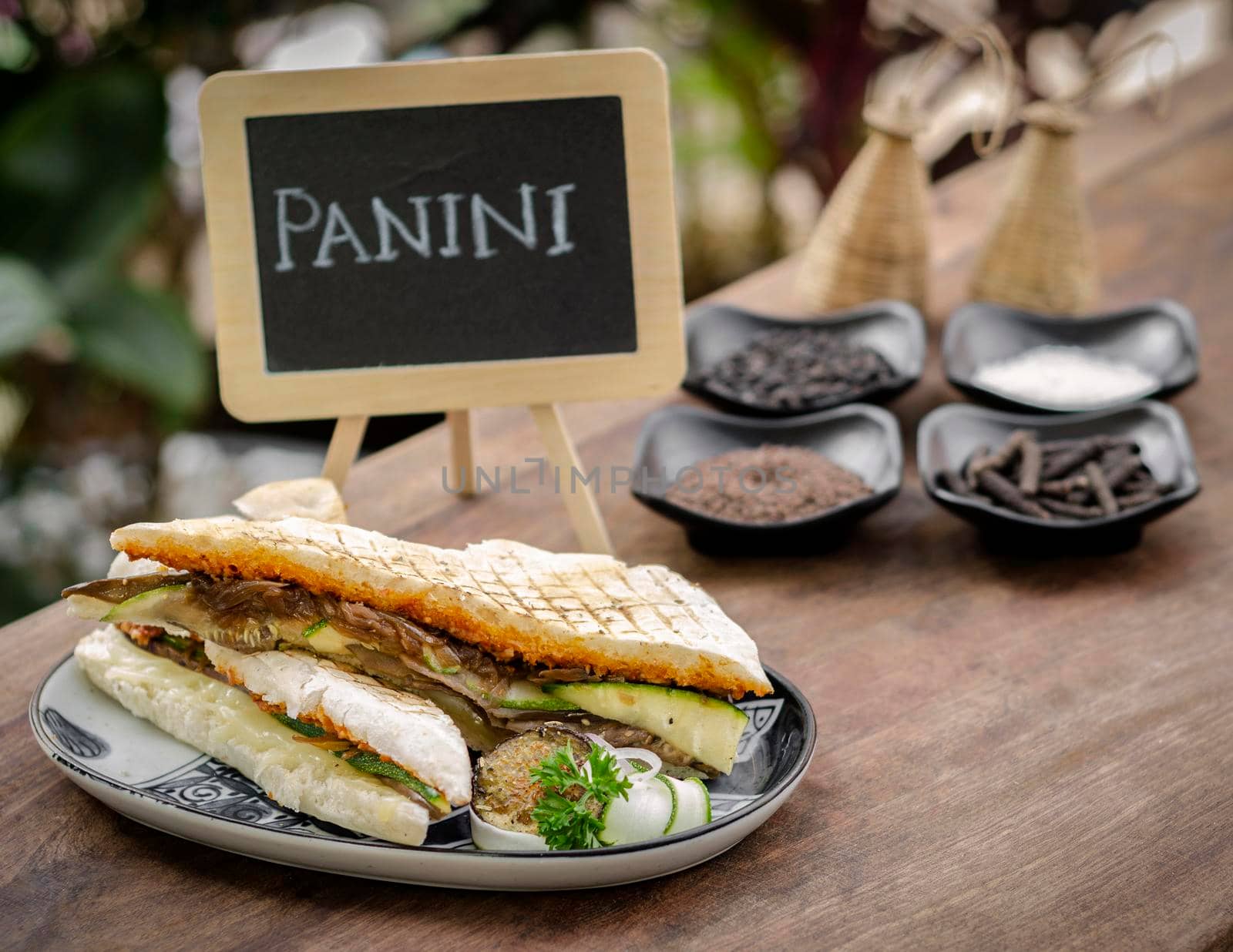 vegan roasted vegetable toasted panini sandwich on wood table outdoors by jackmalipan