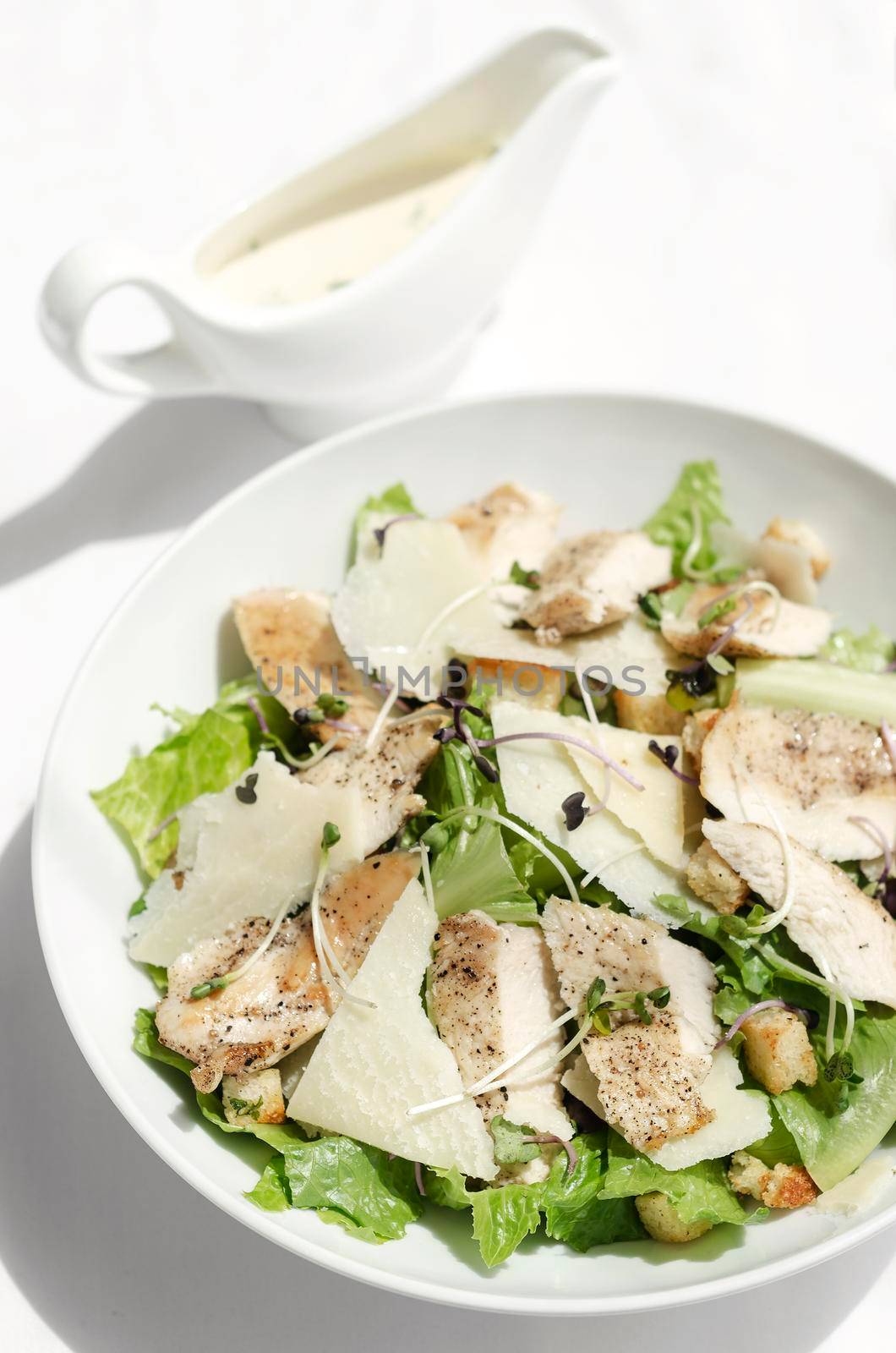 organic chicken caesar salad with parmesan cheese and croutons on white table background