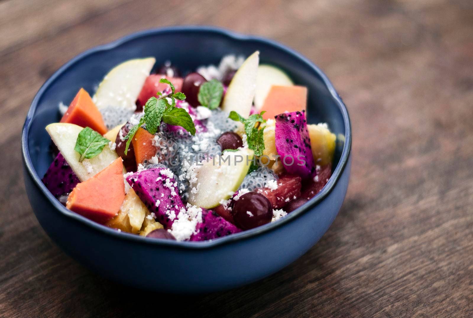 exotic mixed tropical asian fruit salad with basil seeds and coconut in bowl outdoors
