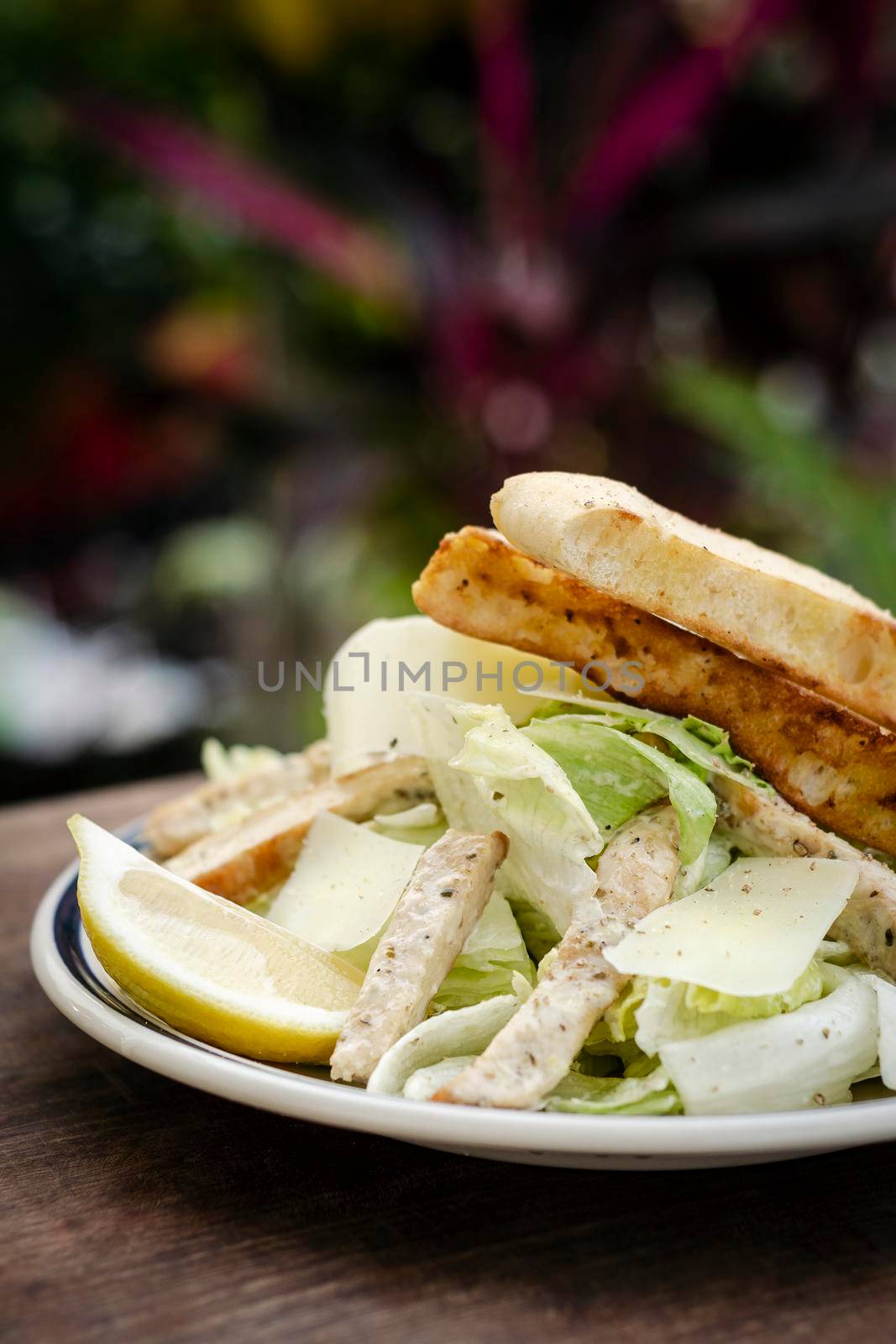 simple healthy chicken caesar salad on wood table  by jackmalipan