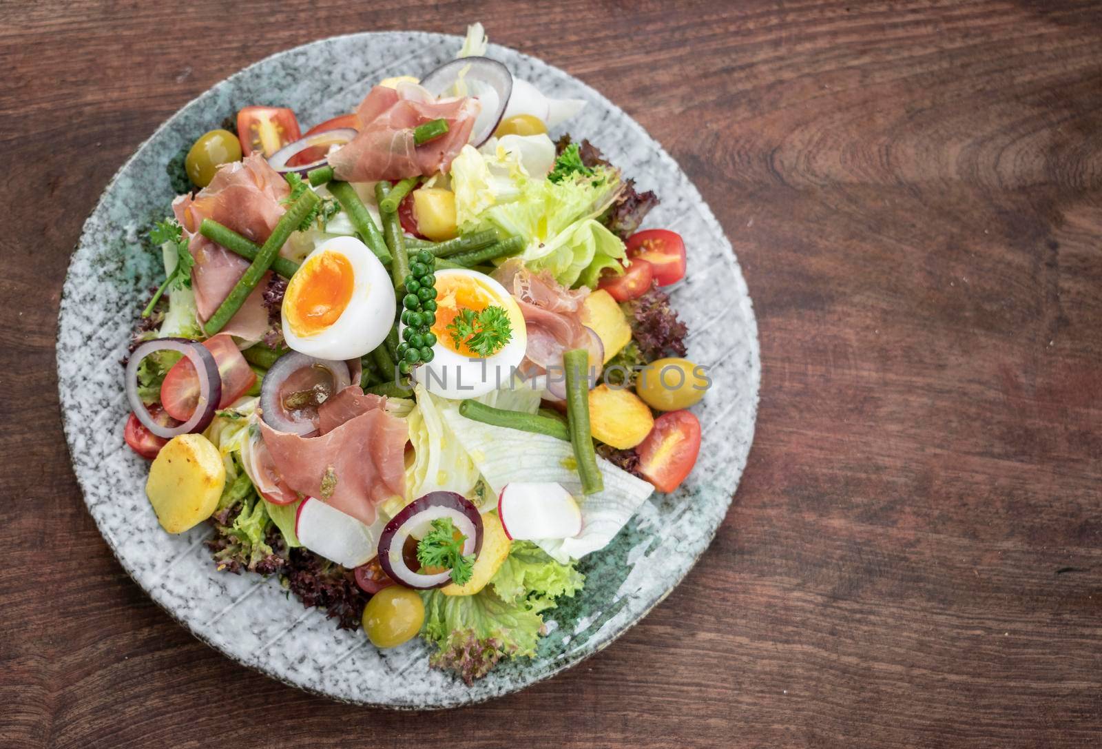 nicoise style healthy organic rustic salad with egg and ham outdoors