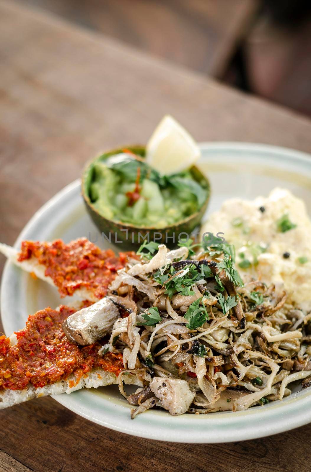 modern mexican brunch of  fried mushrooms with guacamole and spicy red pepper paste toast and scrambled eggs