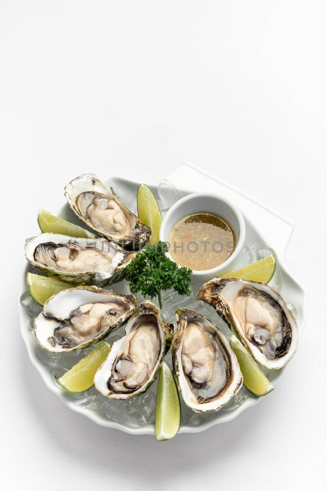 Six fresh oysters with lime wedges and spicy chilli sauce by jackmalipan