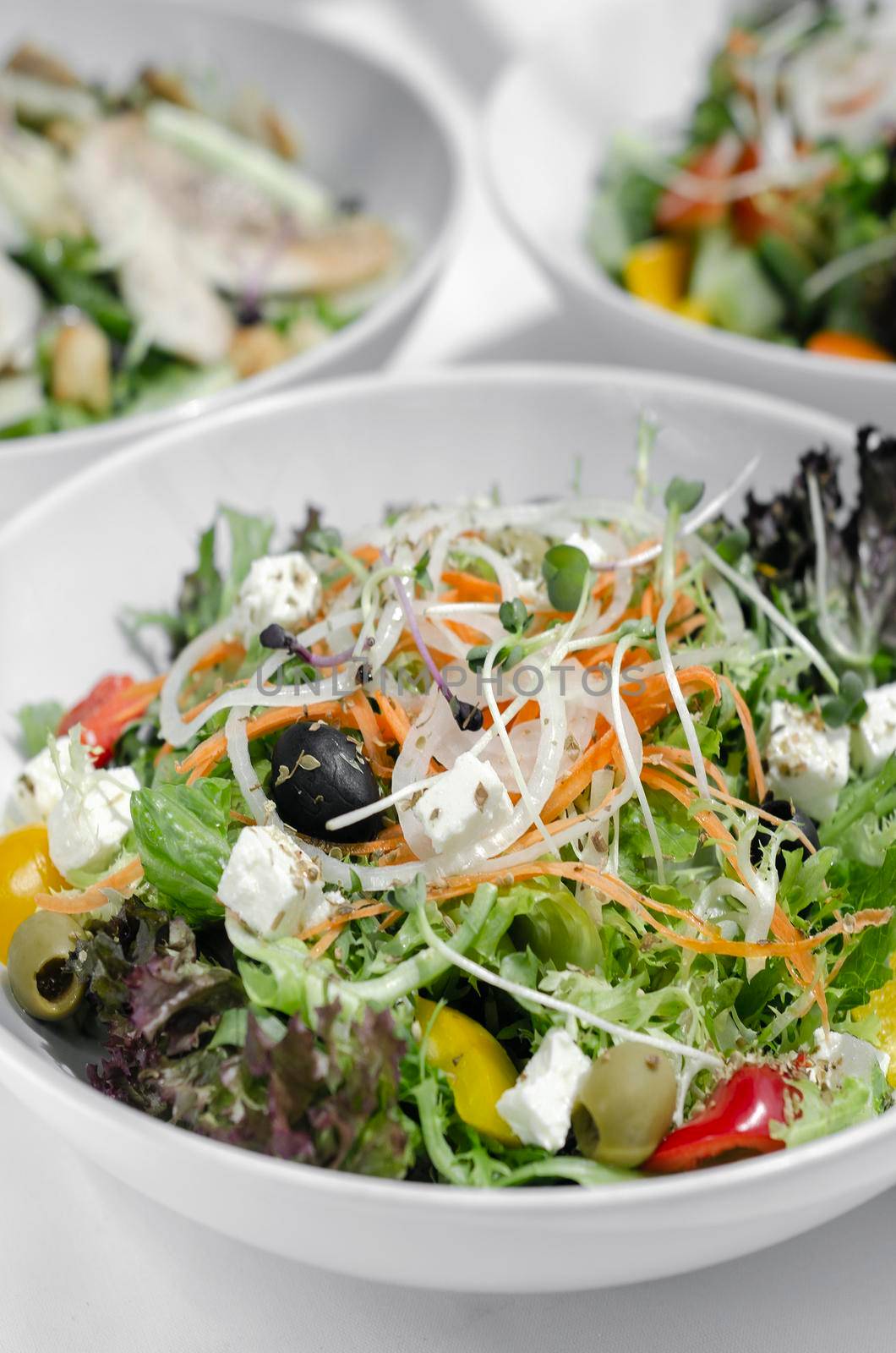 mixed fresh organic salads in bowls on white restaurant table
