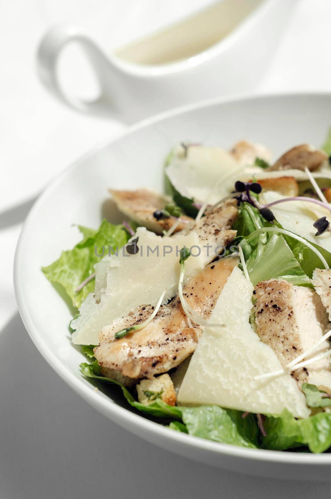 organic chicken caesar salad with parmesan cheese and croutons on white table background