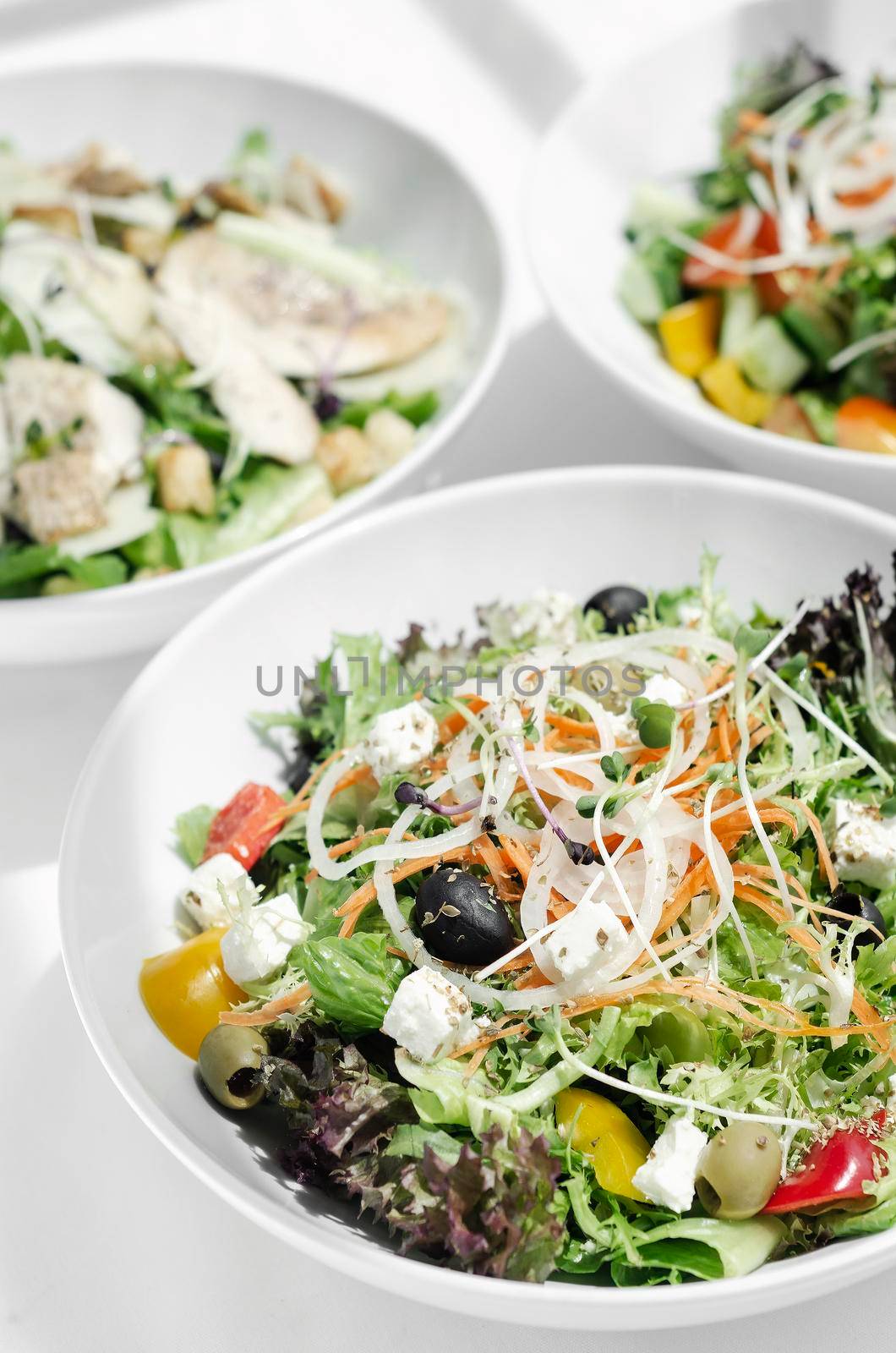 mixed fresh organic salads in bowls on white restaurant table