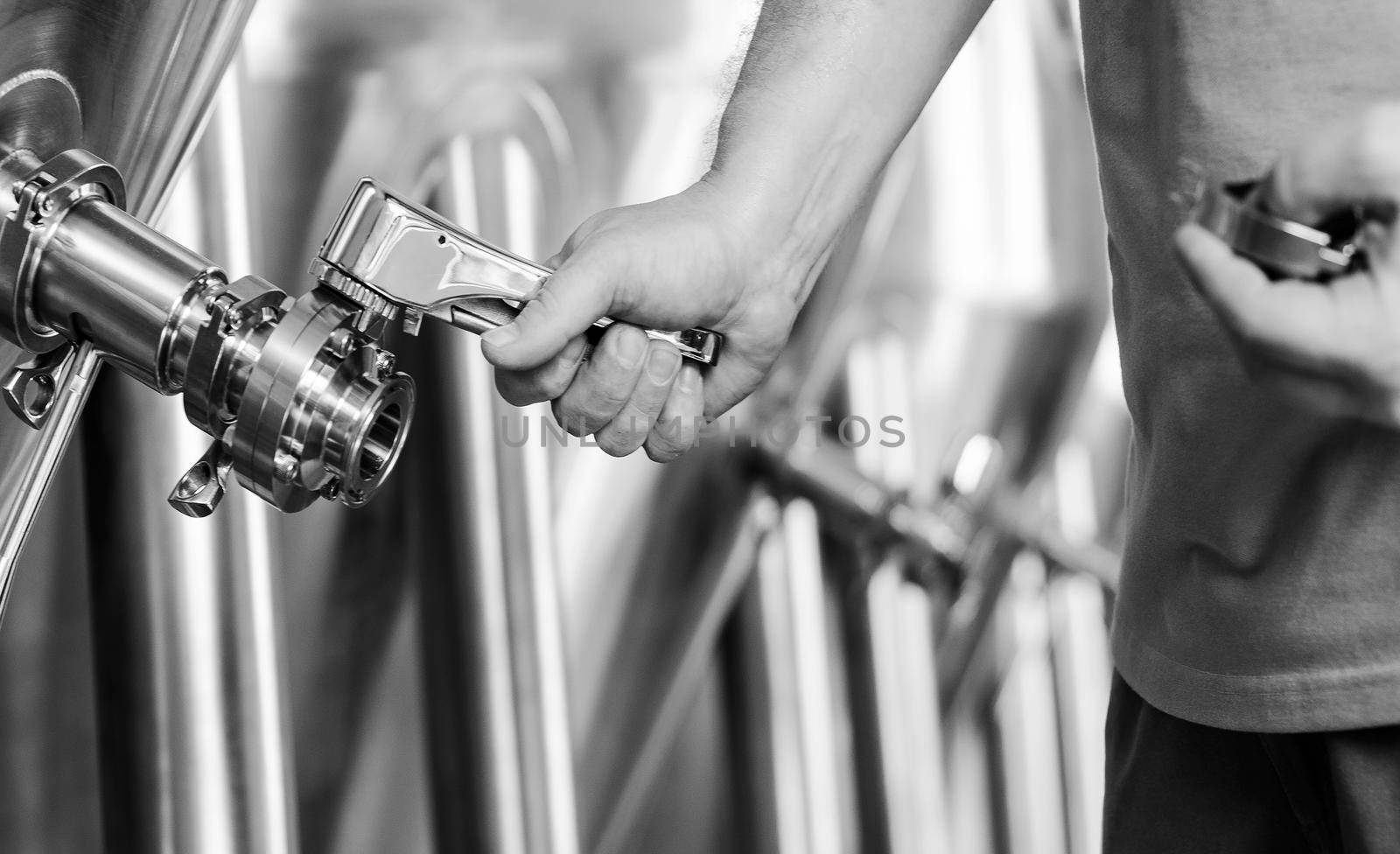 brewer operating industrial beer brewing equipment in brewery interior in black and white