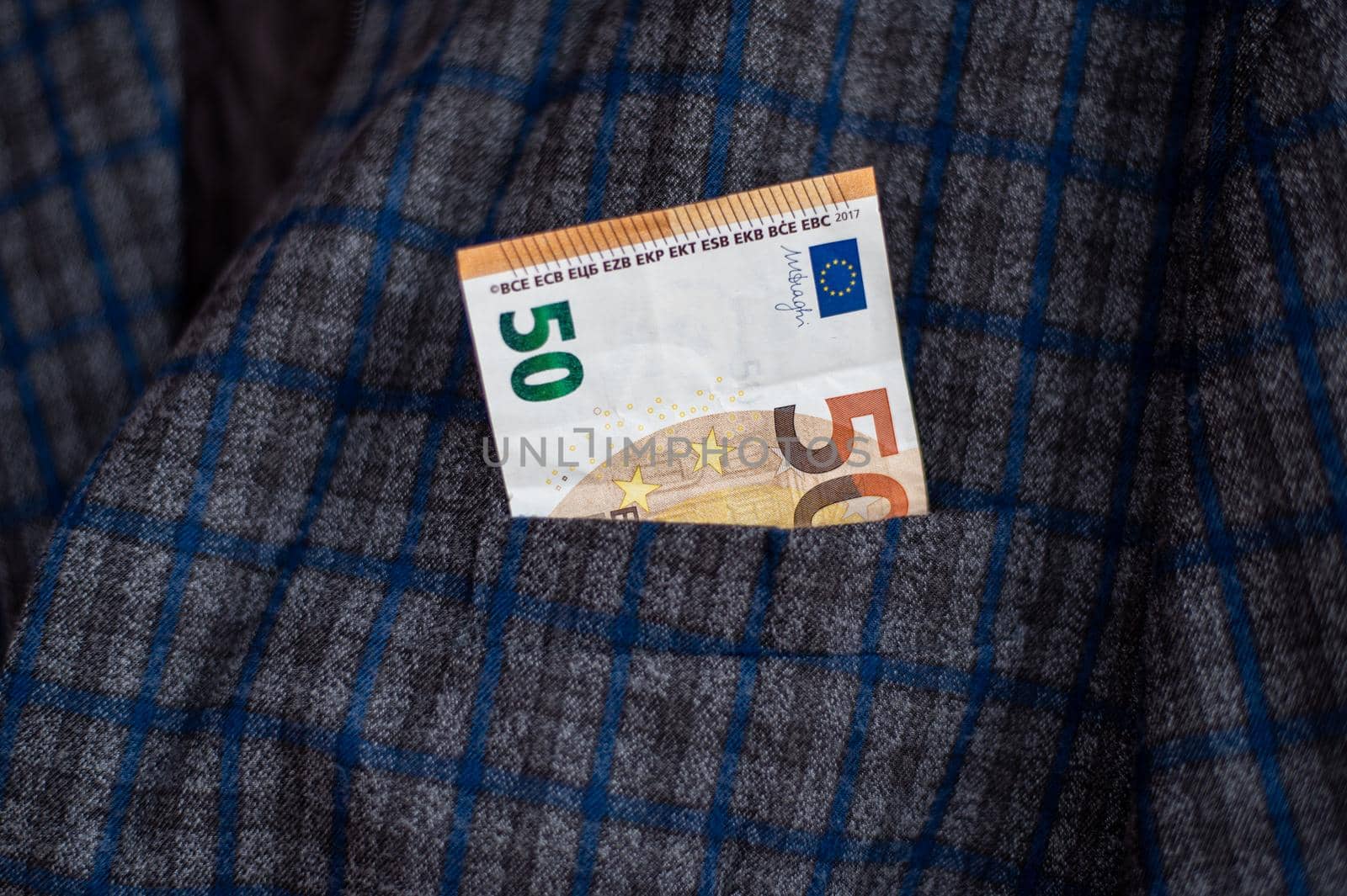pocket of the plaid jacket coming out of 50 euro bills