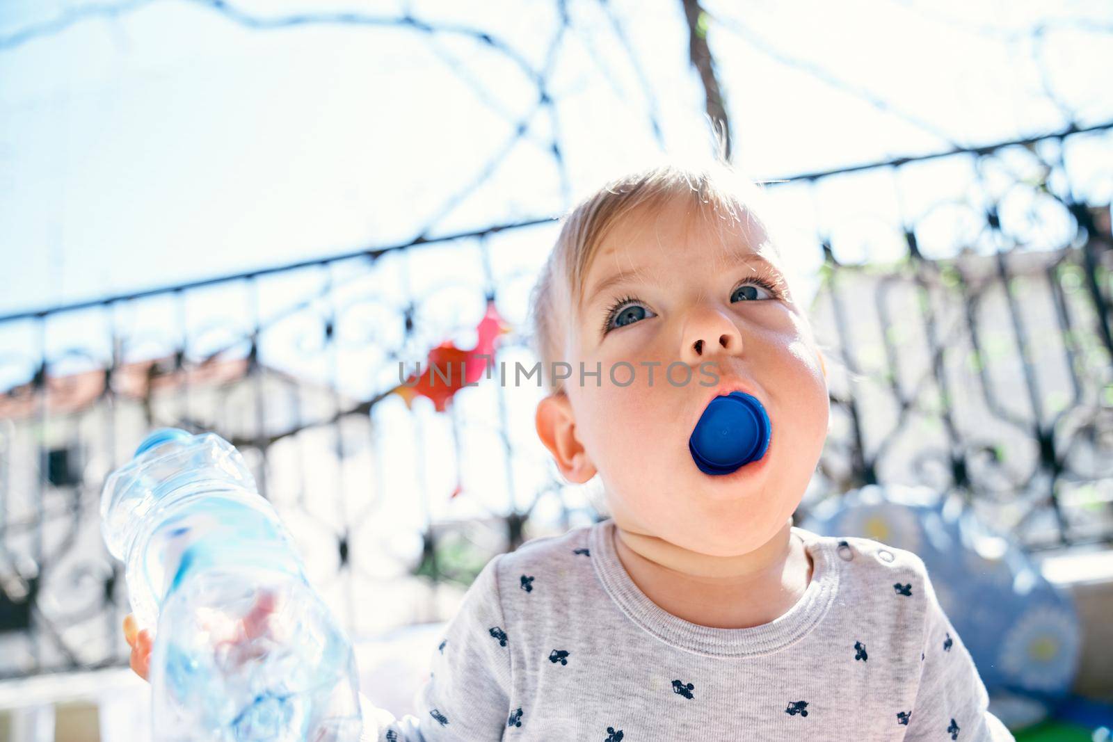 Small child stuffed a plastic bottle cap into his mouth, which he is holding in his hand. High quality photo