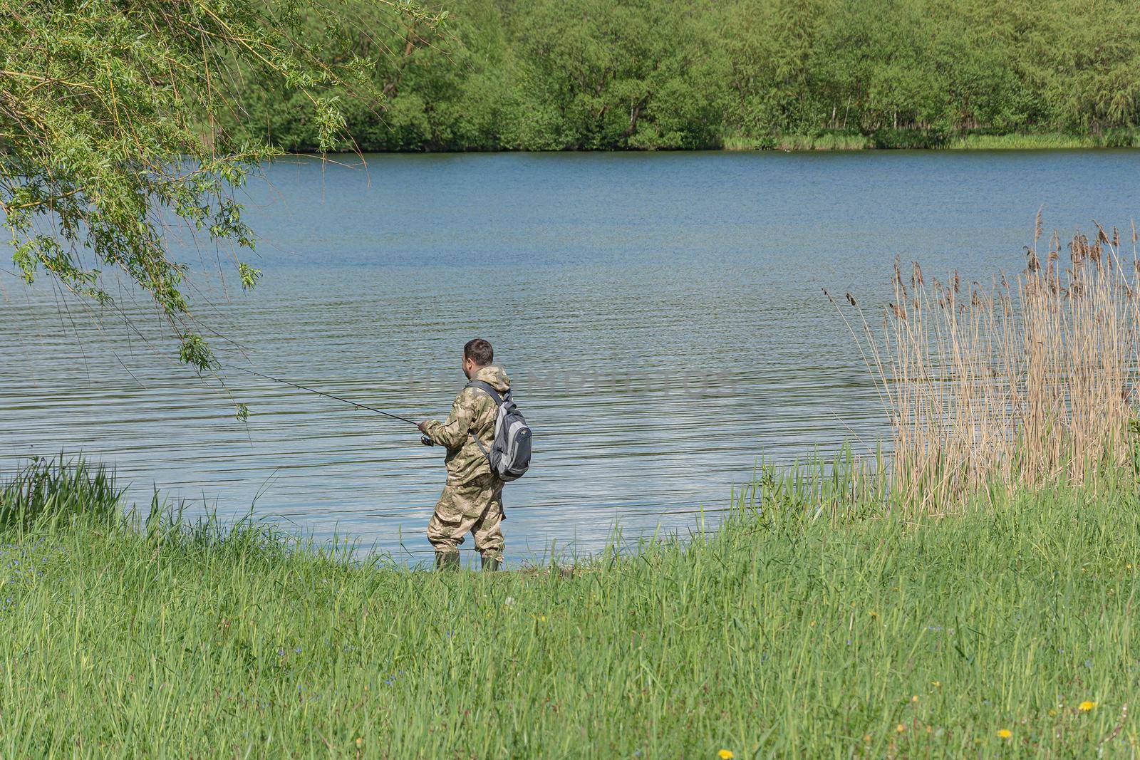 A fisherman catches fish on the river bank. Stock photo.