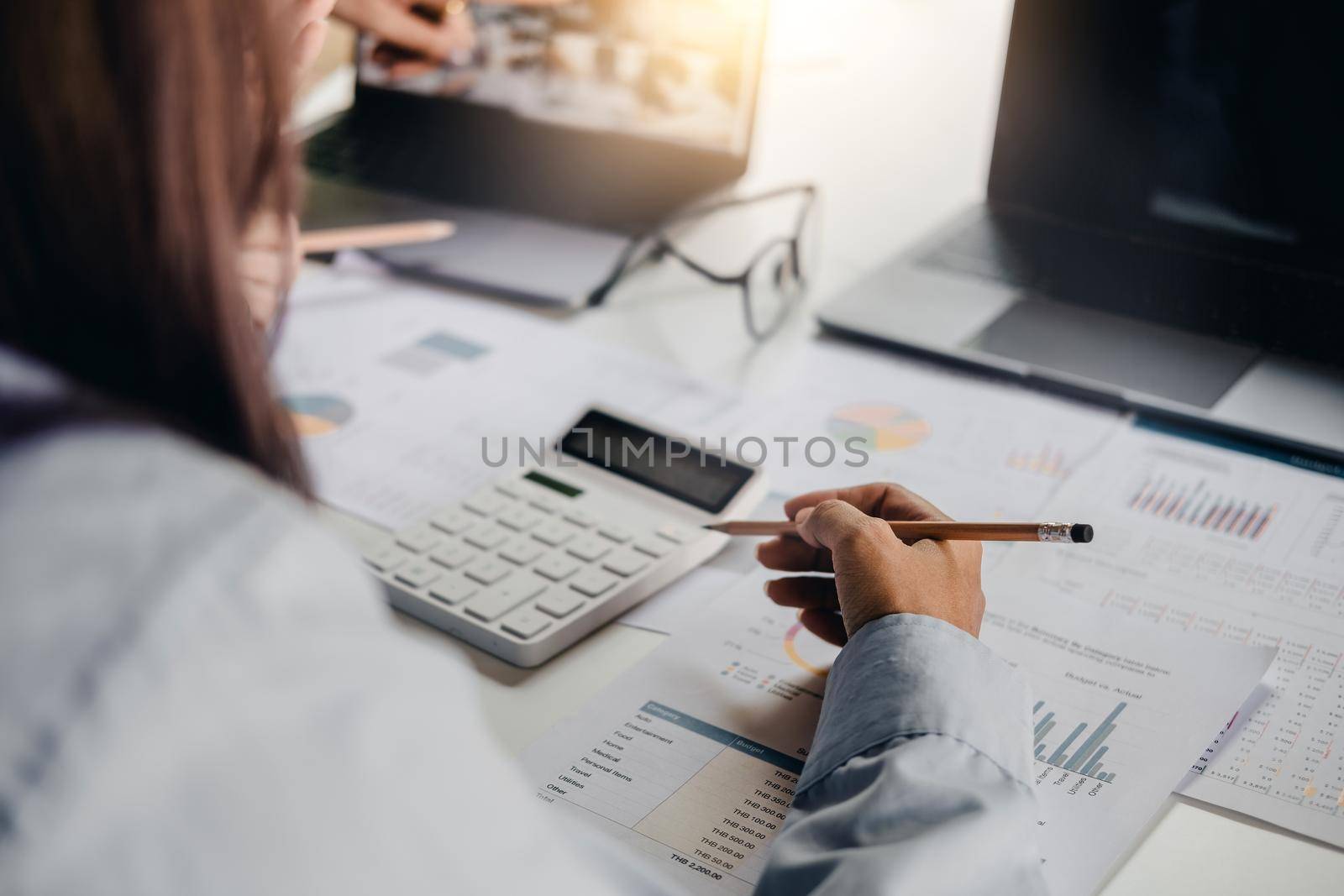 Business woman working with calculator and laptop computer for finance and accounting Analyze financial budget in the office. by nateemee