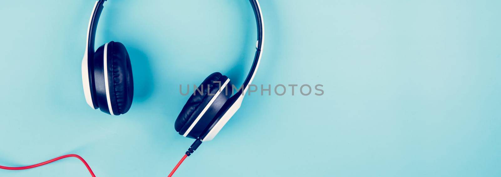 Headphones with music isolated on blue background, device headset and sound stereo, equipment entertainment, listening communication, flat lay, top view, nobody, electronic accessory object.