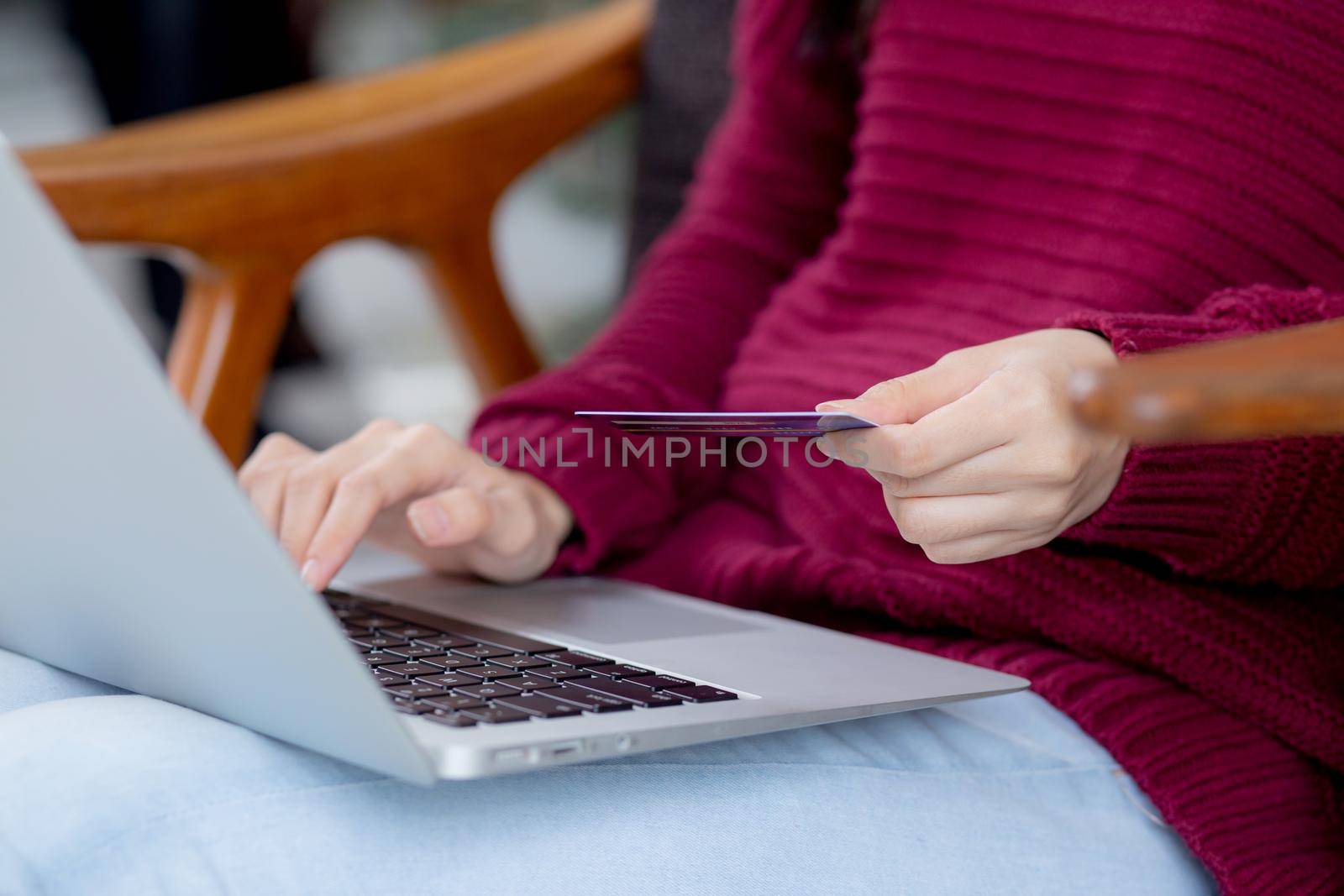 Closeup hand of young asian woman online shopping in Christmas with credit card on laptop computer, female buying and payment with debit card, xmas in holiday, happy new year, customer with purchase.