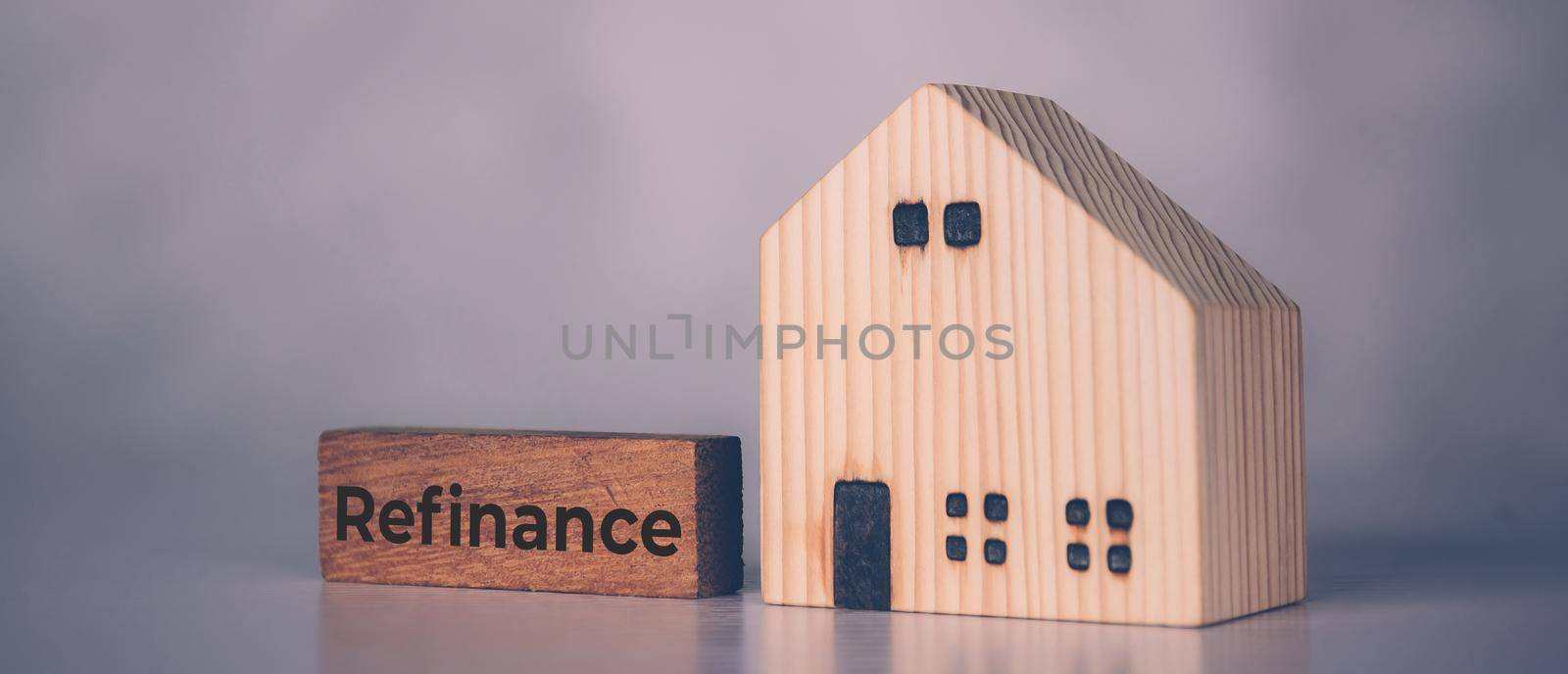 Wooden block with refinance word and house model about home and finance, loan and mortgage for real estate and property, residential and planning with budget, investment and earning, business concept. by nnudoo