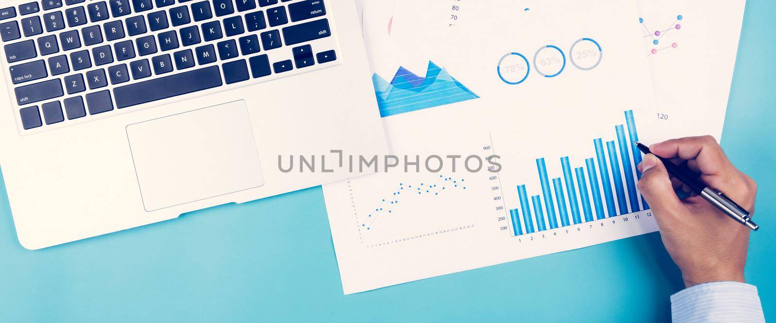 Hand of businessman looking documents report statistic financial with graph and chart and laptop computer on desk, finance and invest, digital marketing, business and communication concept.