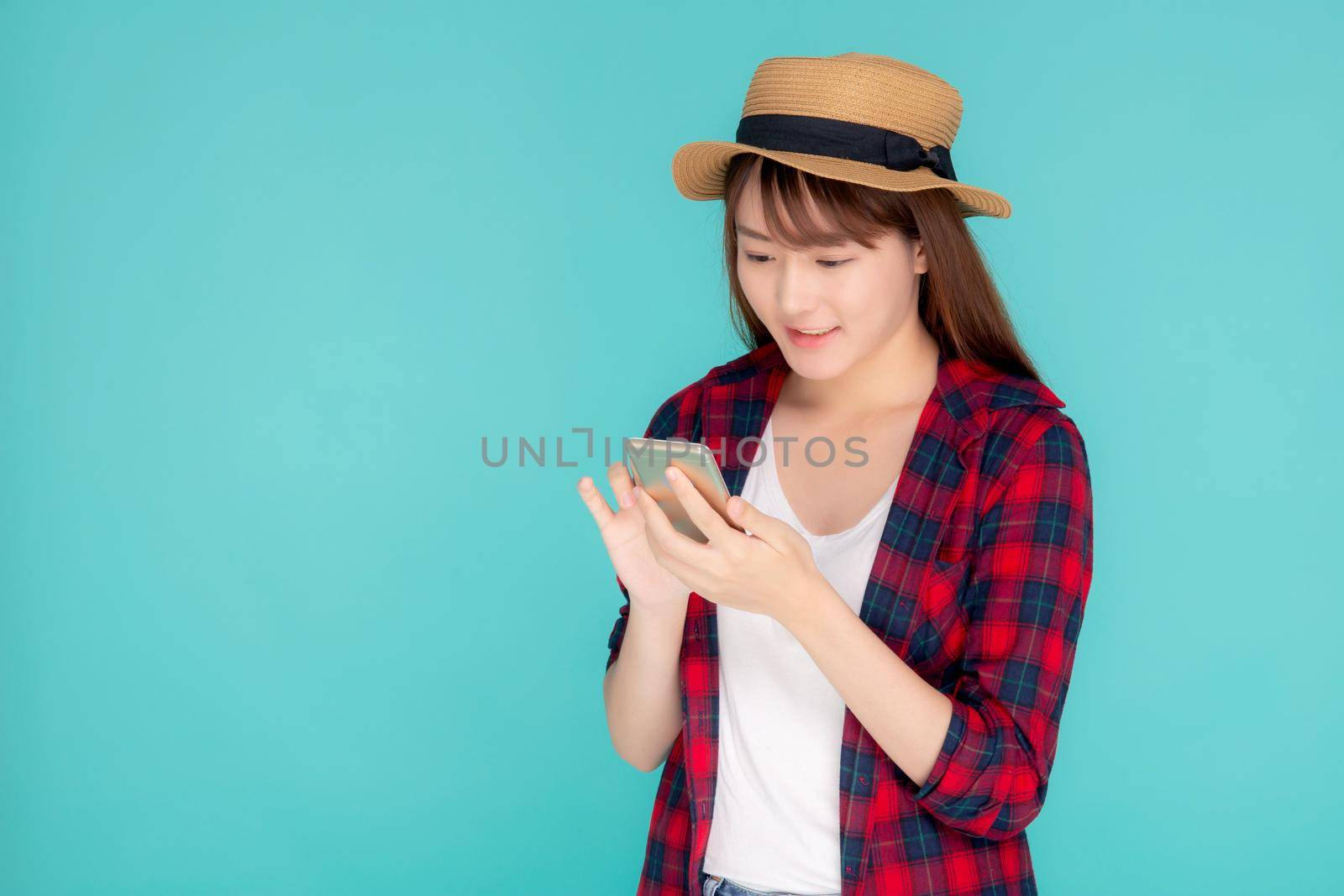Beautiful young asian woman touch smart mobile phone in vacation isolated on blue background, asia girl talking or chat message on smartphone in travel summer trip, journey or education concept.