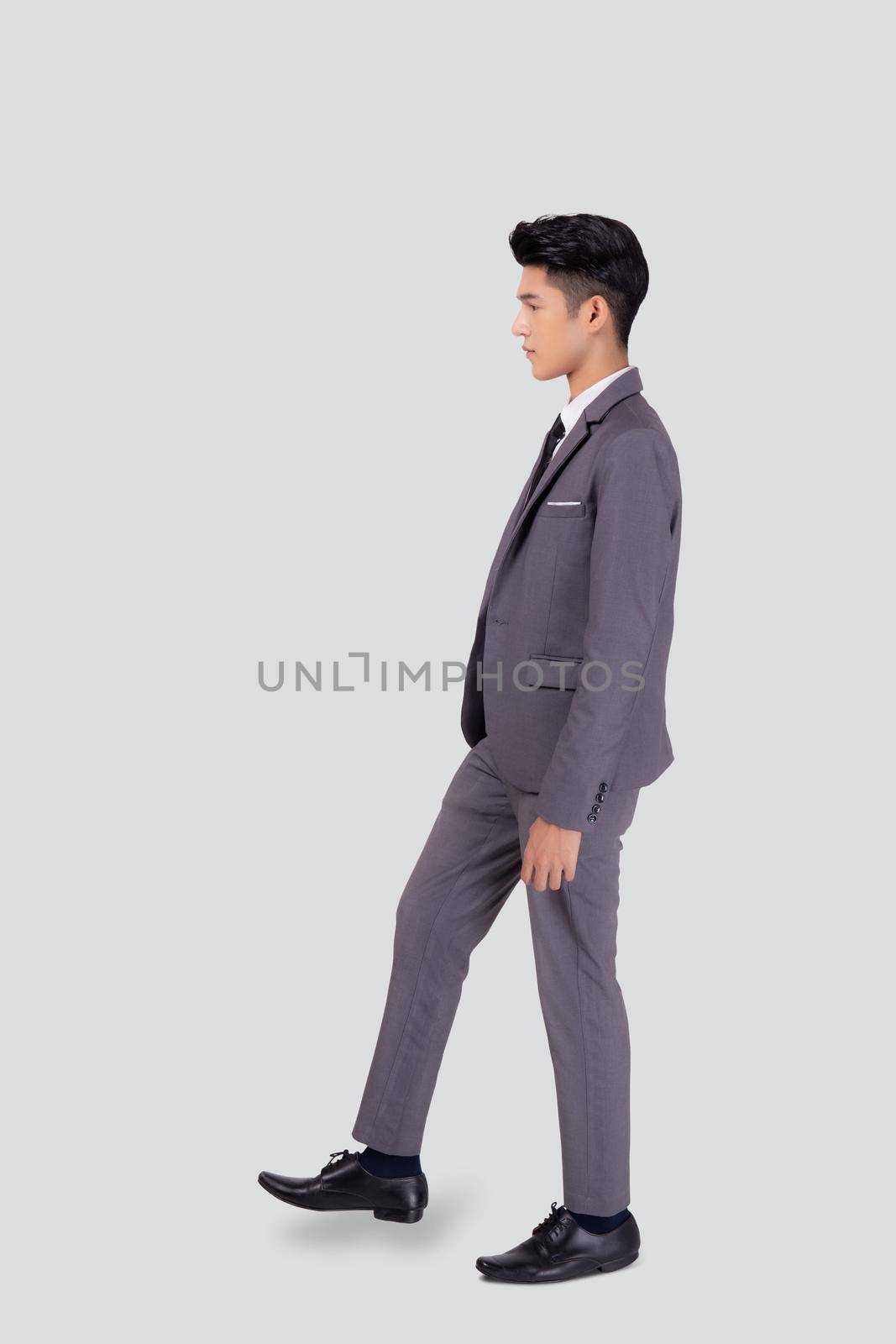 Young asian business man in suit walking movement isolated on white background, portrait of executive or manager, happy businessman handsome and smart, male with confident for success in studio. by nnudoo