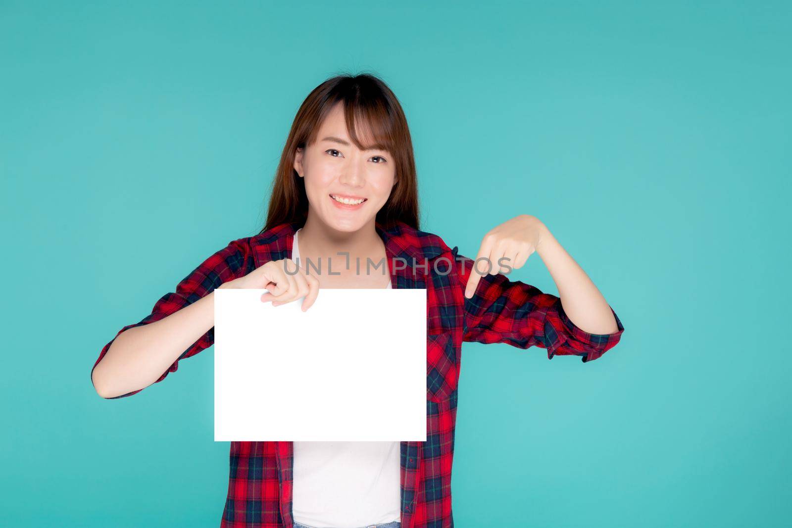 Beautiful portrait young asian woman presenting with blank paper sheet, asia girl wear travel summer fashion with happy pointing empty board or card isolated on blue background. by nnudoo