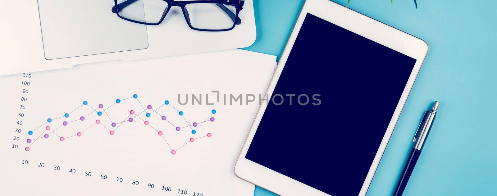 Laptop computer and documents report statistic financial with graph and chart and glasses and tablet, finance and invest, digital marketing and growth of revenue, business and communication concept. by nnudoo