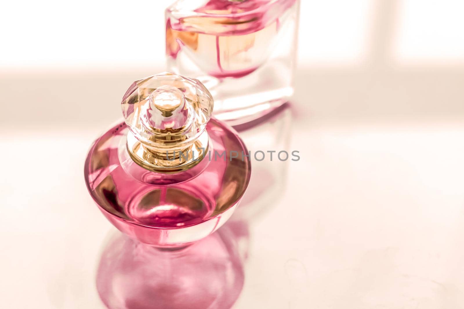 Perfumery, spa and branding concept - Pink perfume bottle on glossy background, sweet floral scent, glamour fragrance and eau de parfum as holiday gift and luxury beauty cosmetics brand design