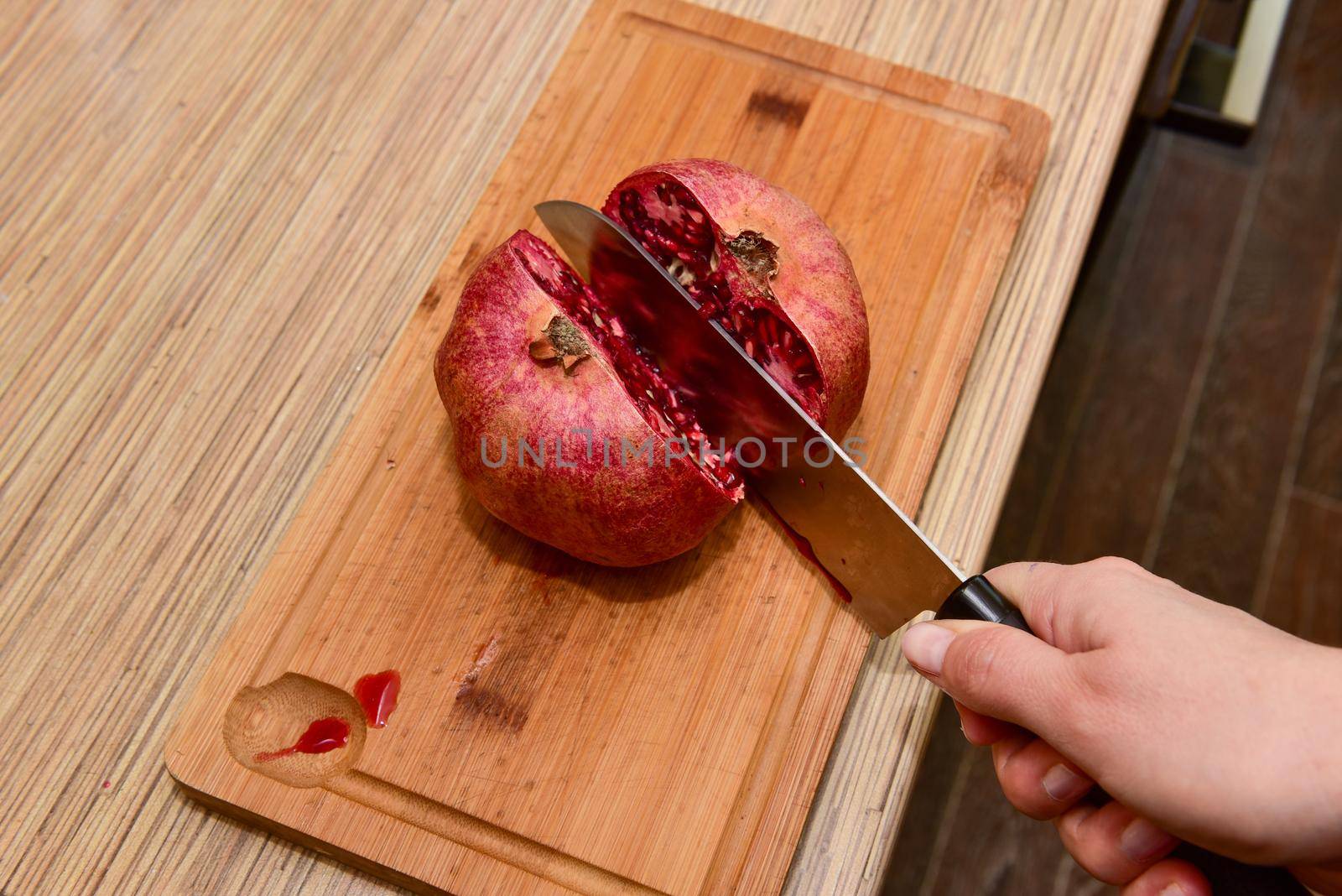 Female hands Cutting pomegranate in a kitchen. Close-up.