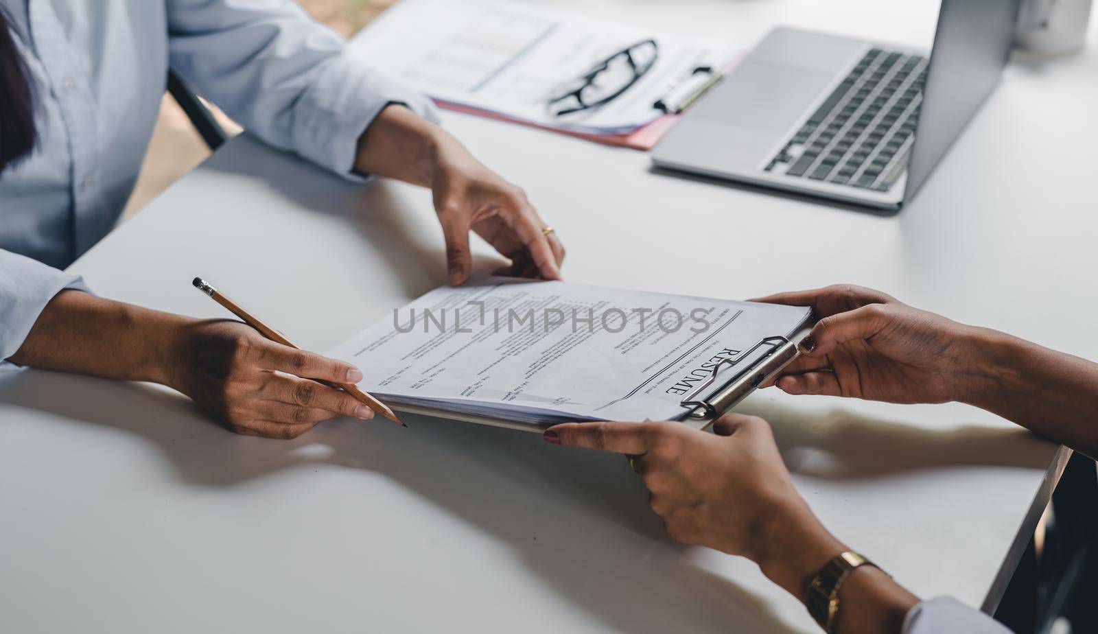 Businesswoman holding resume and talking to female candidate, during corporate meeting or job interview - business, career and placement concept. by nateemee