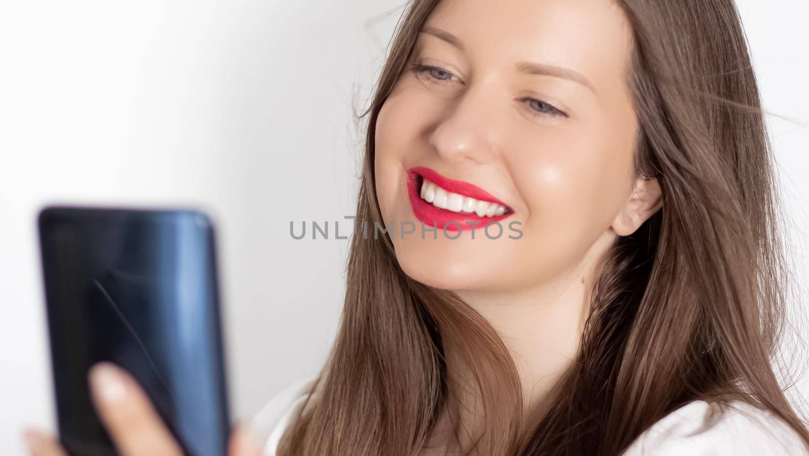 Happy smiling woman with smartphone having video call or taking selfie, portrait on white background. People, technology and communication concept.