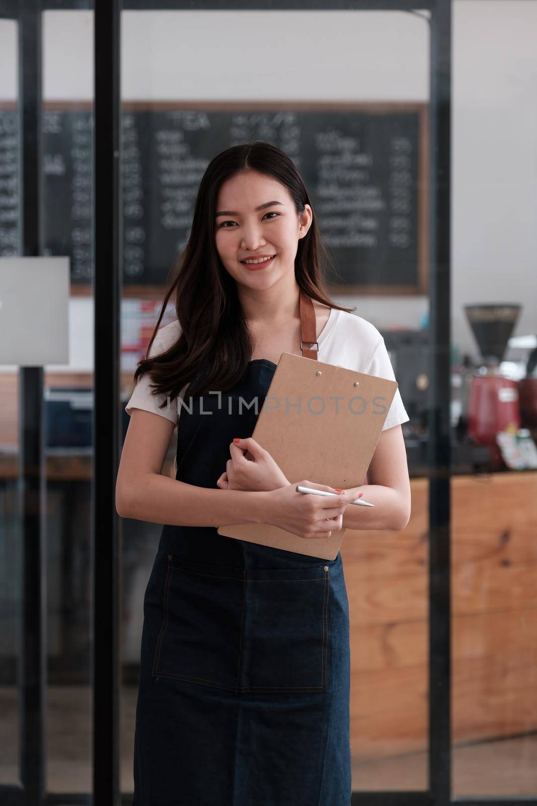 At her coffee shop, the business owner or barista with menu and waiting order from first customer back to open the shop after COVID-19