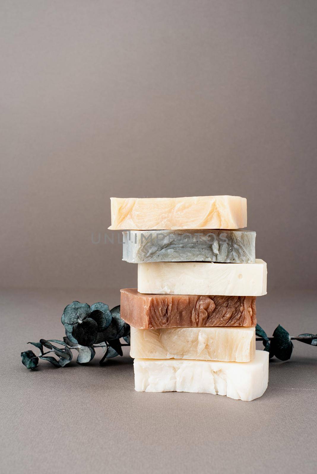Stack of various handmade soap and eucalyptus on gray background, front view