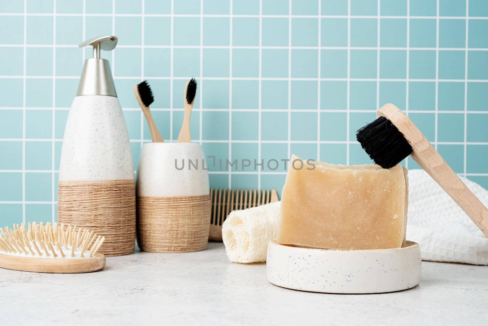 Bath accessories with bamboo brushes, handmade soap, dispenser and natural brushes on bath shelf, front view