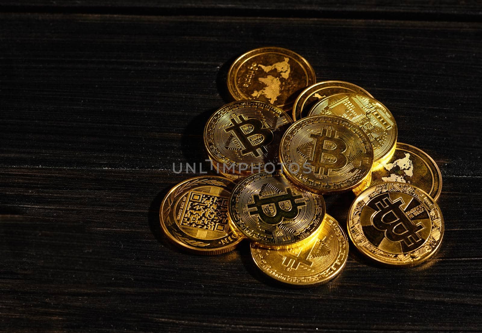 Leader in cryptocurrency bitcoin BTC on a top of coins against black wooden surface. Closeup golden coin with bitcoin logo. Stack of decentralized digital currency. Crypto payment. Electronic money